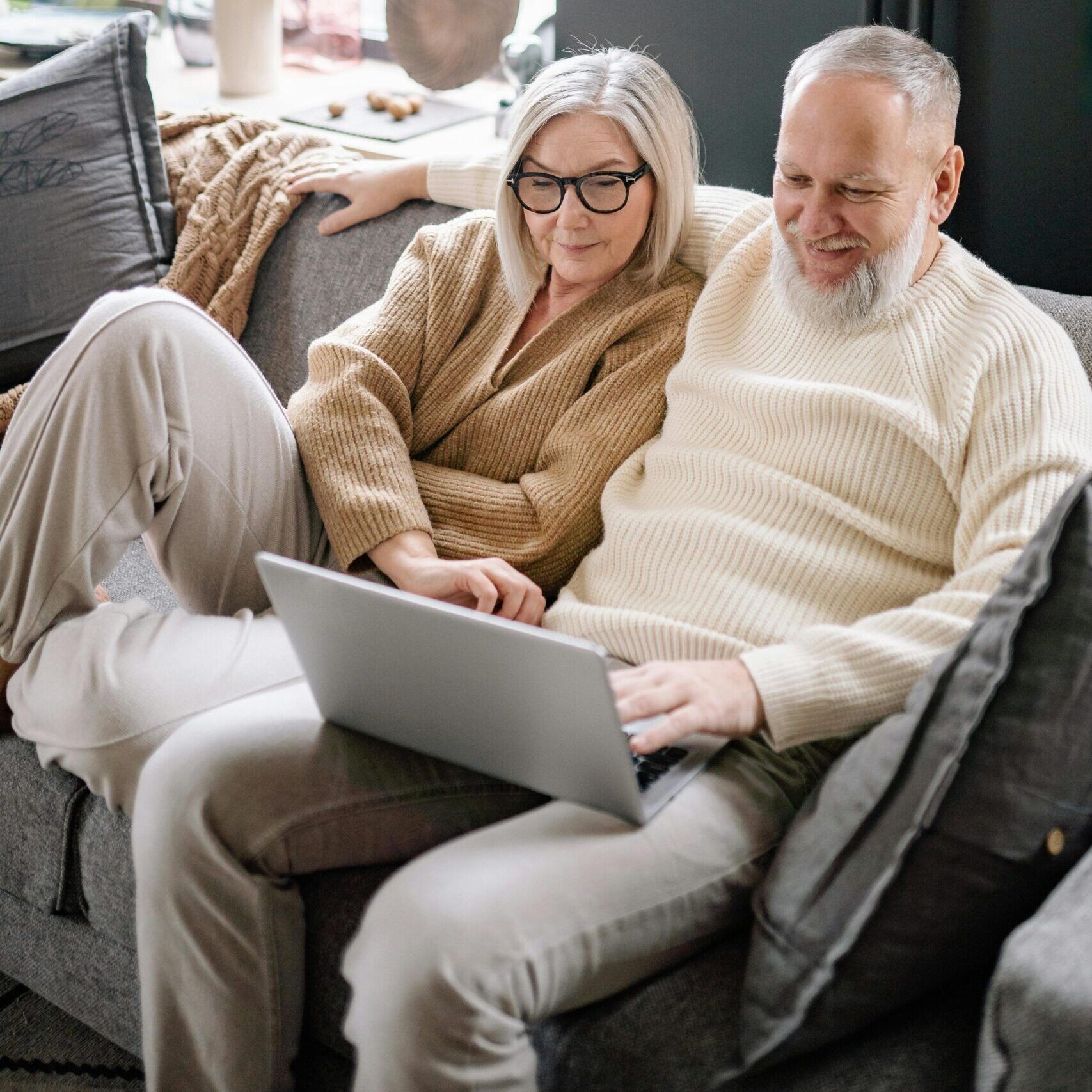 Couple on a couch looking at a laptop stock photo