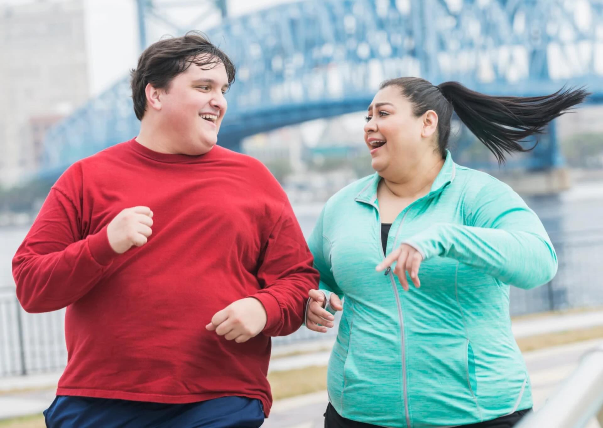 Balanced Hormone Health – December 2025 Blog Images – 2026-Kickstart-Why-December-Is-the-Best-Month-to-Begin-GLP-1 Man and woman jogging outdoors together, smiling and exercising near a bridge.