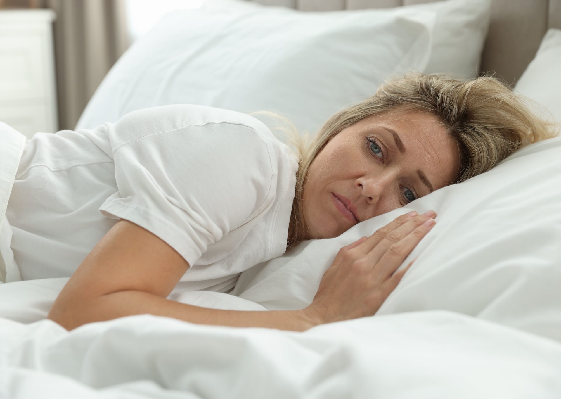 Tired woman lying in bed with difficulty sleeping