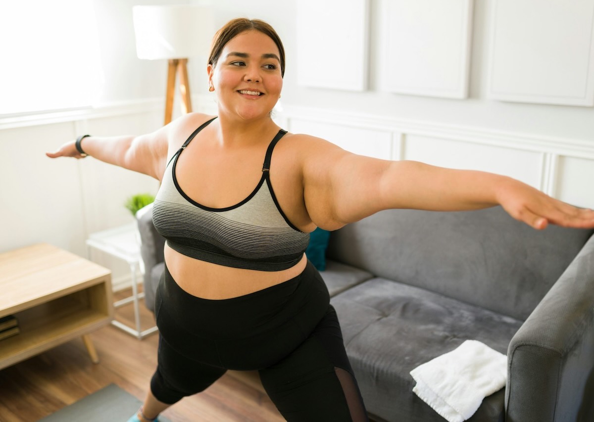 Woman exercising at home with arms extended, representing new year weight loss goals focused on balance, consistency, and realistic progress.