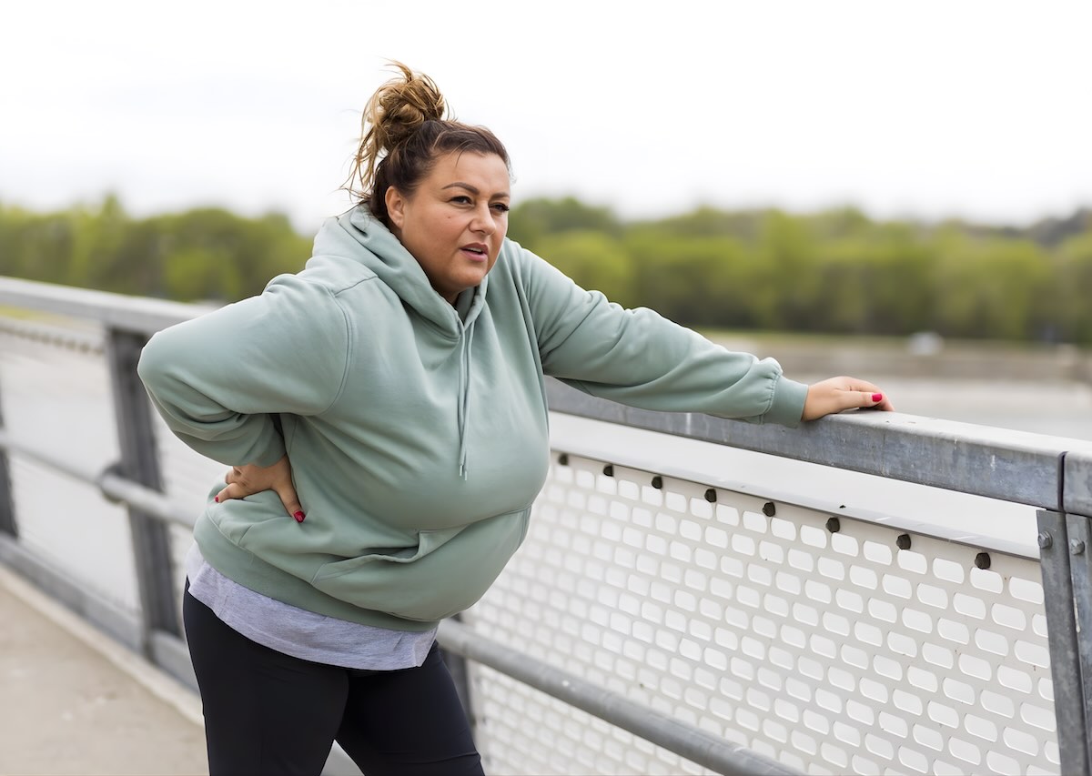 Woman pausing during outdoor exercise, representing the challenge of a weight loss plateau and the need for support to break through.