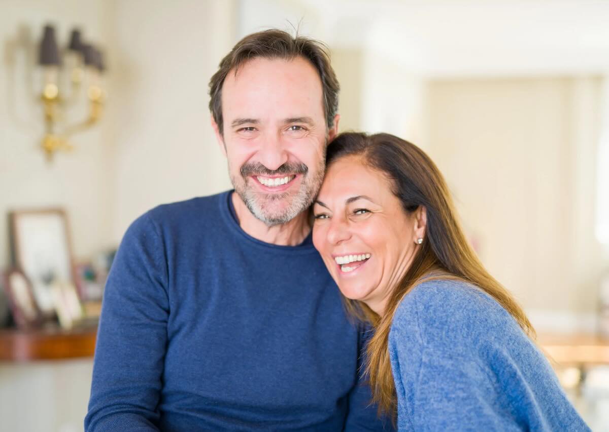 Smiling couple standing close together in a bright home setting.