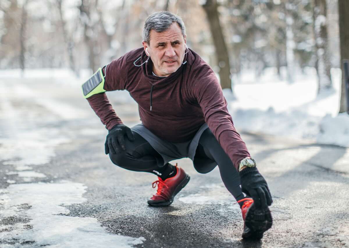 Balanced Hormone Health – February 2026 Blog Images – Winter-Slump-How-Medical-Weight-Loss-Keeps-Progress-Going Man stretching outdoors on a snowy path during a winter workout.