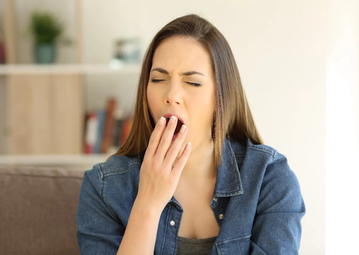 Woman yawning at home showing symptoms of spring fatigue and low seasonal energy.