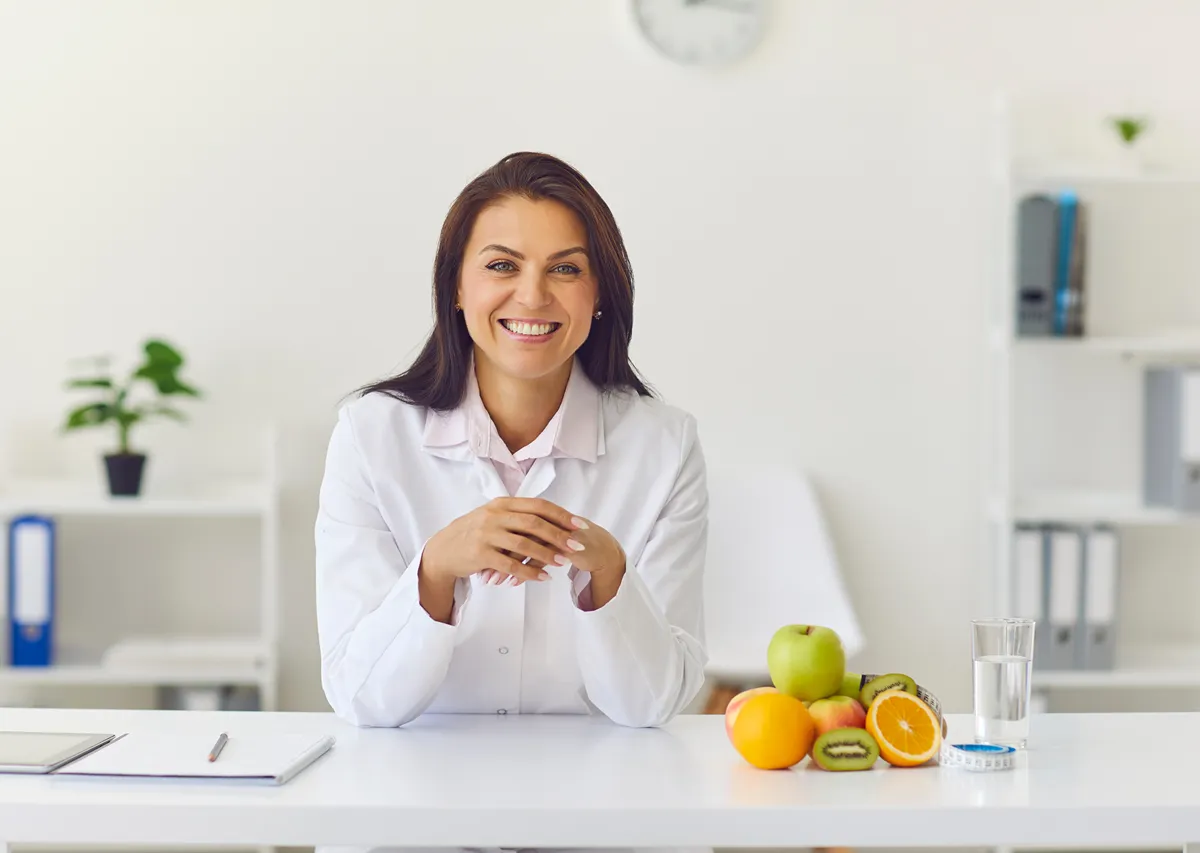 10-Symptoms-That-May-Mean-Its-Time-To-Have-Your-Hormones-Checked woman sitting at a table smiling