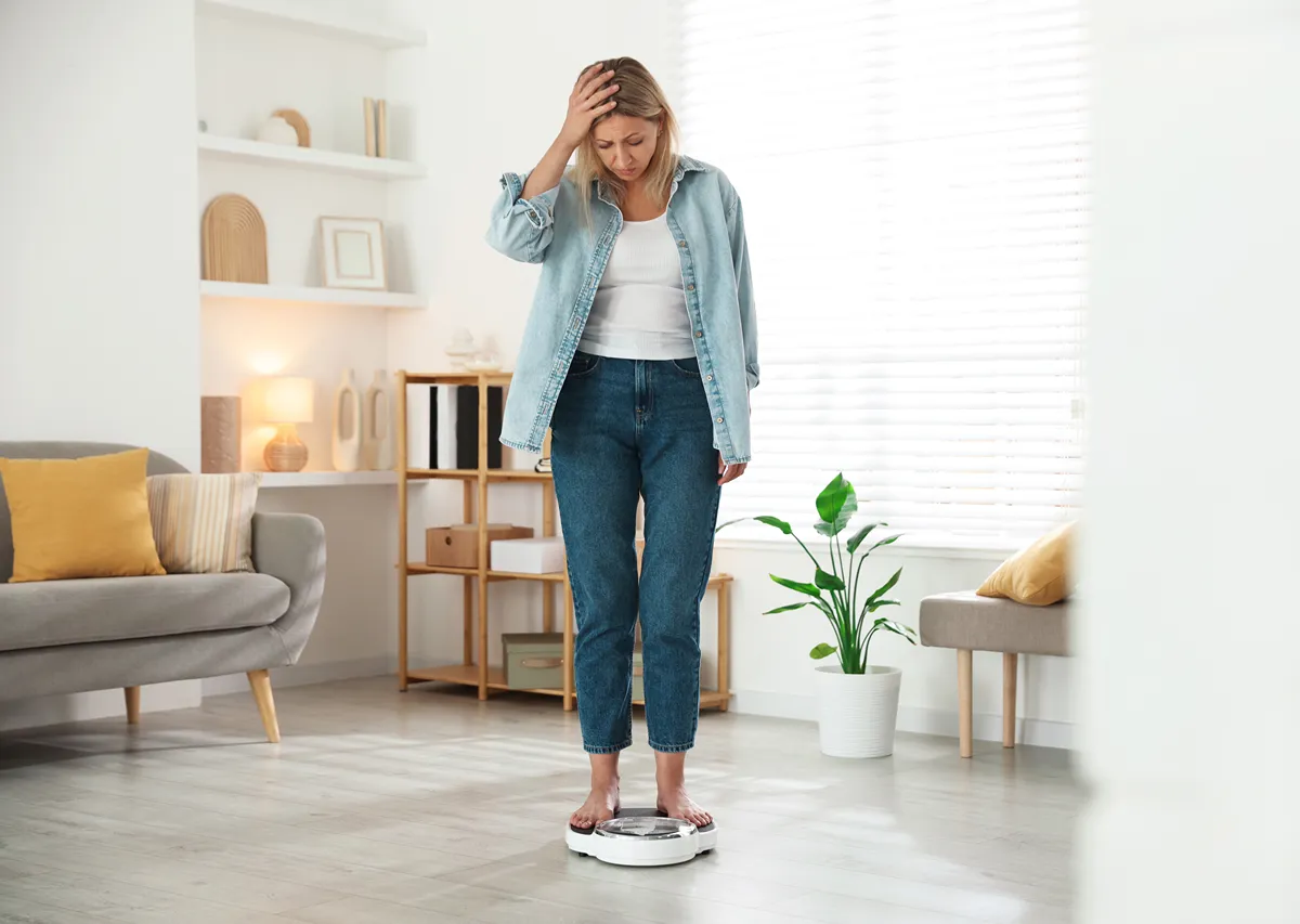 woman starting at a scale distressed about her weight