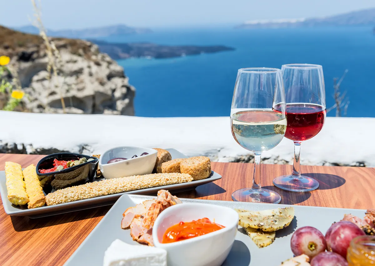 Vacation-Without-The-Weight-Gain-Healthy-Travel-Tips-That-Actually-Work a set table in front of the ocean with drinks and food