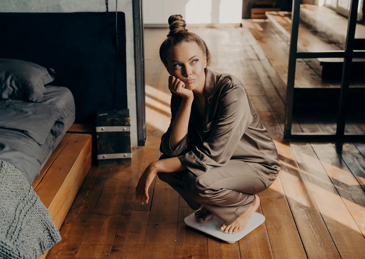 woman squatting on a scale looking out the window